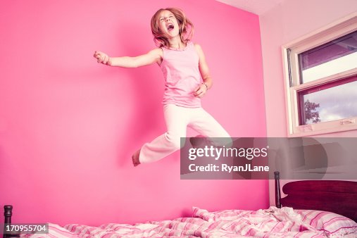 Fille sautant sur un lit en rose chambre Fille sautant sur un lit en rose chambre