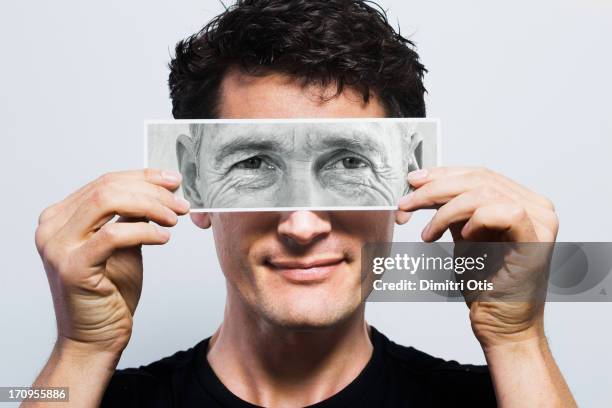 young man holding picture of old eyes over his - dementeren stockfoto's en -beelden