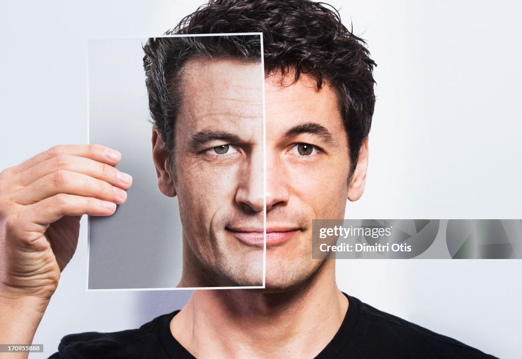 Man holding portrait of older version of himself