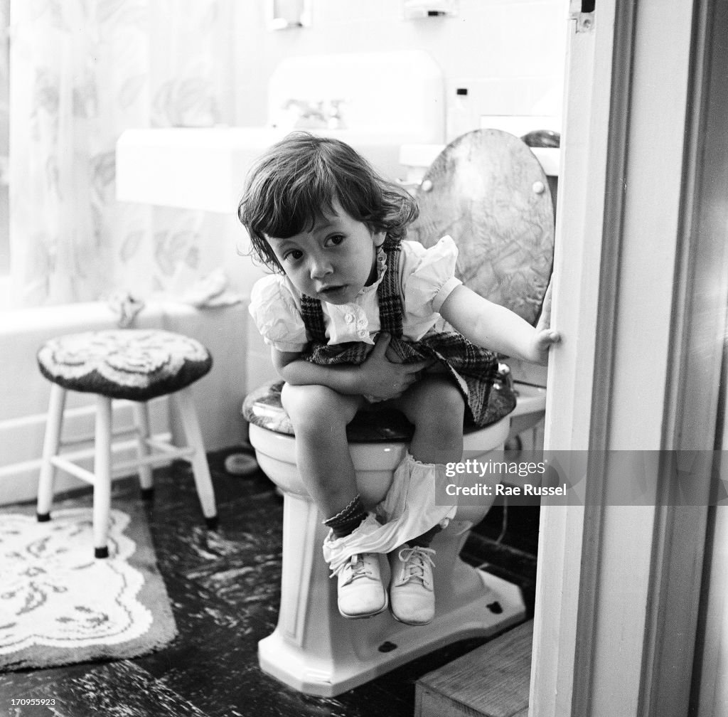 Little girl on toilet View of an unidentified young girl, seated on a toilet, and peeking... News Photo - Getty Images