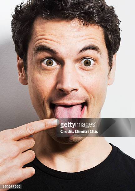 portrait of man pointing to his tongue - sticking out tongue stock pictures, royalty-free photos & images
