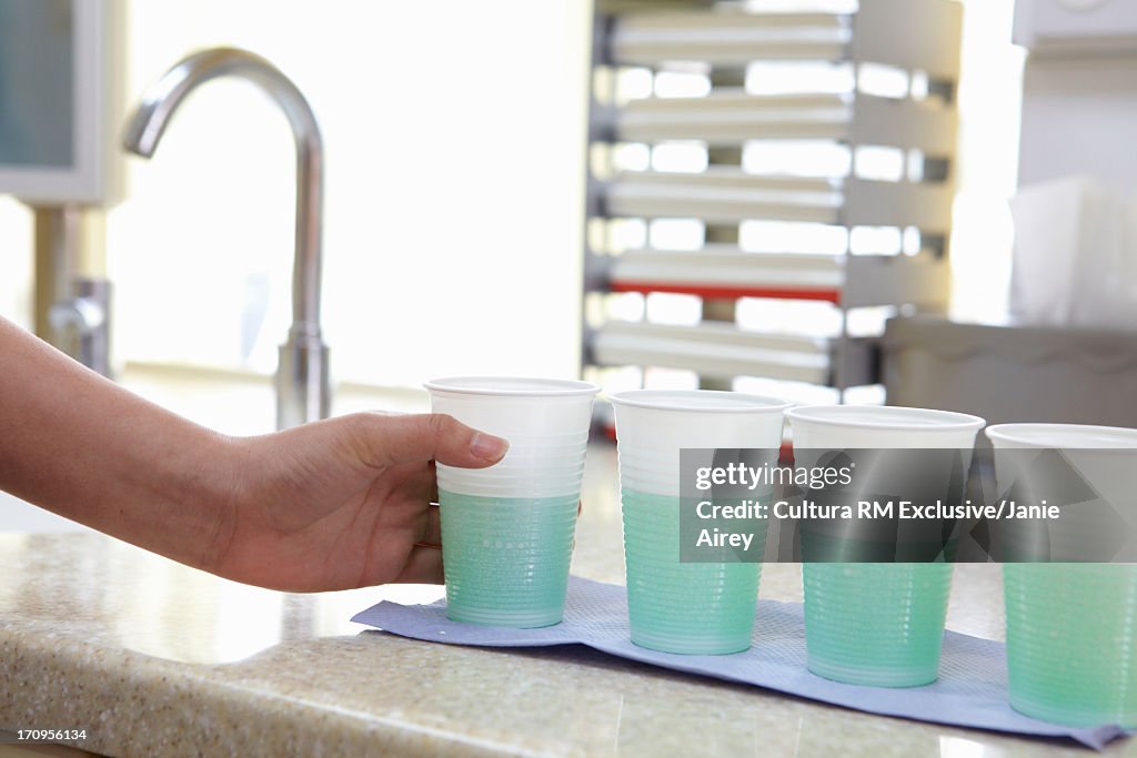 Dental assistant preparing cups of mouth rinse