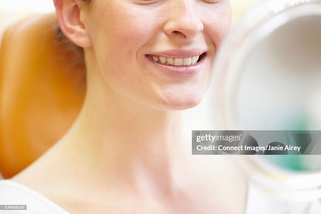 Dental patient smiling and looking in mirror