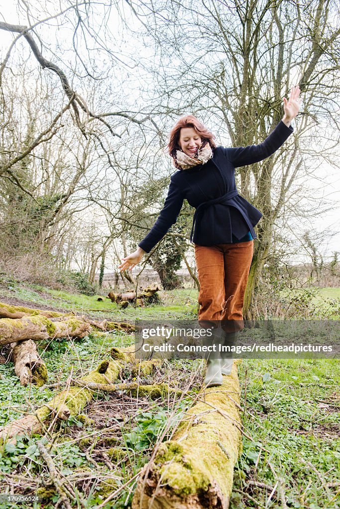 Woman balancing along tree trunk