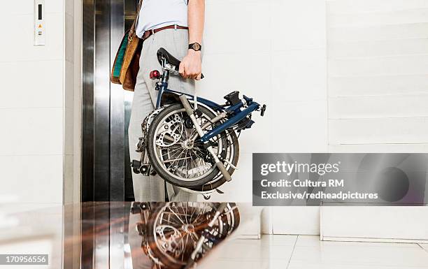man with folding bicycle by elevator - klapprad business stock-fotos und bilder