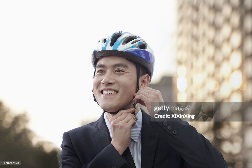 Businessman putting on cycling helmet