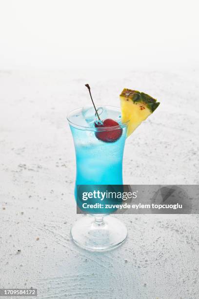 blue ice cold cocktail with cherry and slice of pineapple - blue curacao stock pictures, royalty-free photos & images
