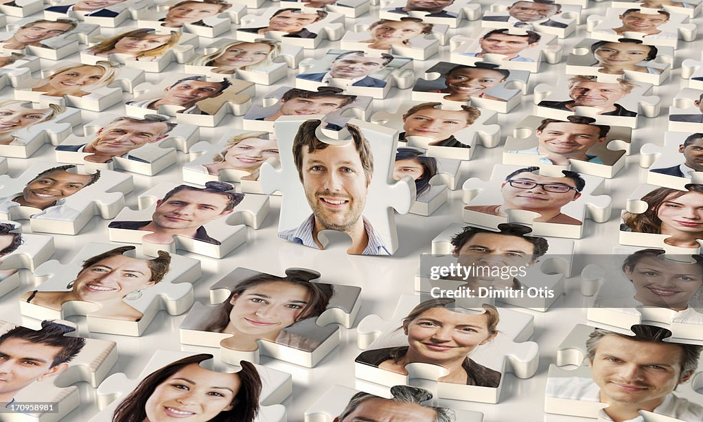 Puzzle pieces of faces, one standing up