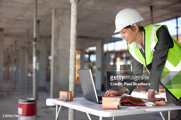 trabajador de la construcción usando una computadora portátil en solar de construcción - built structure fotografías e imágenes de stock