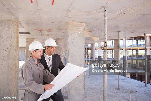 construction workers looking at blueprints on construction site - architekt helm plan stock pictures, royalty-free photos & images