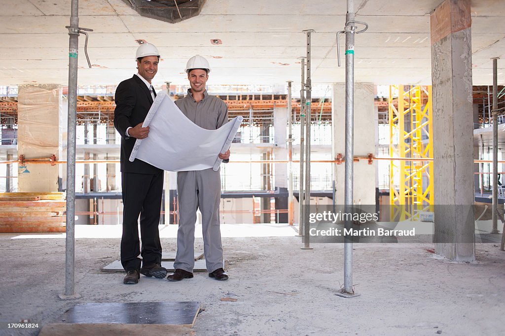 Trabajadores de la construcción mirando blueprints en solar de construcción