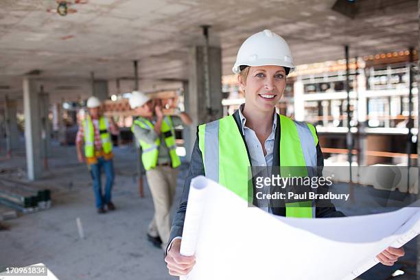 construction worker holding blueprints on construction site - architekt helm plan stock pictures, royalty-free photos & images