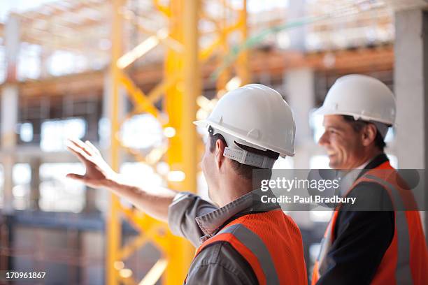 bauarbeiter arbeiten auf baustelle - schutzhelm stock-fotos und bilder