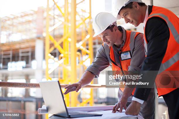 operai utilizzando un computer portatile su luogo di costruzione - construction site foto e immagini stock