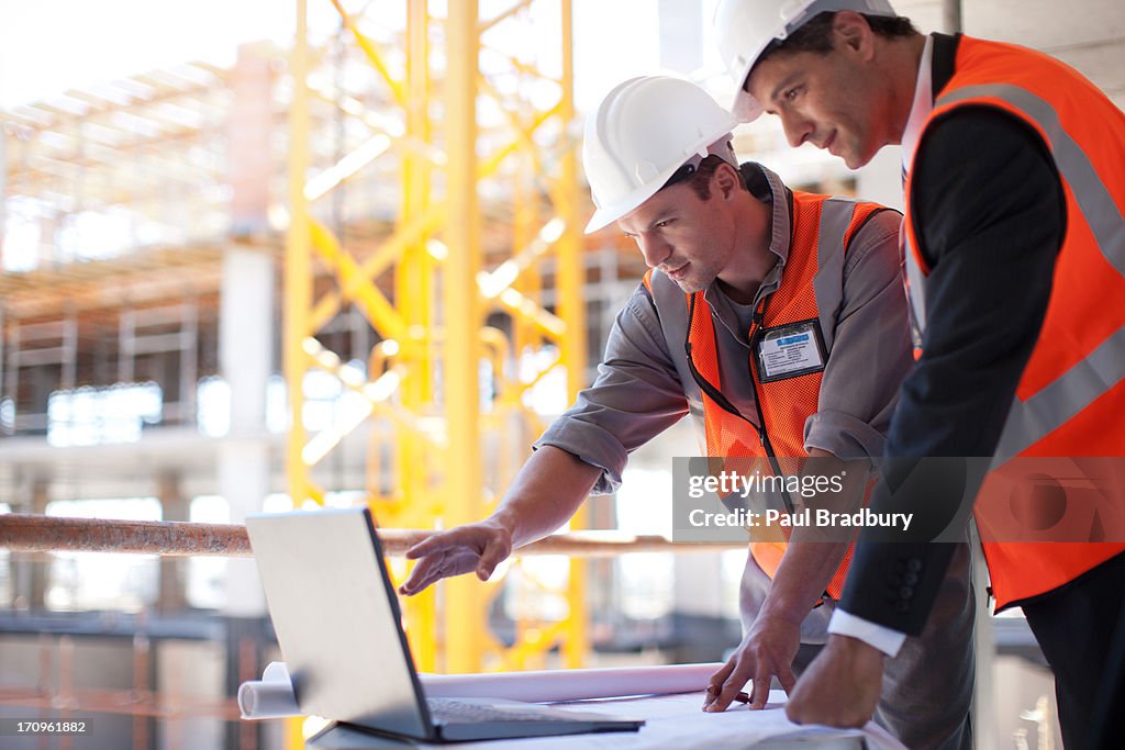 Construction workers using laptop on construction site