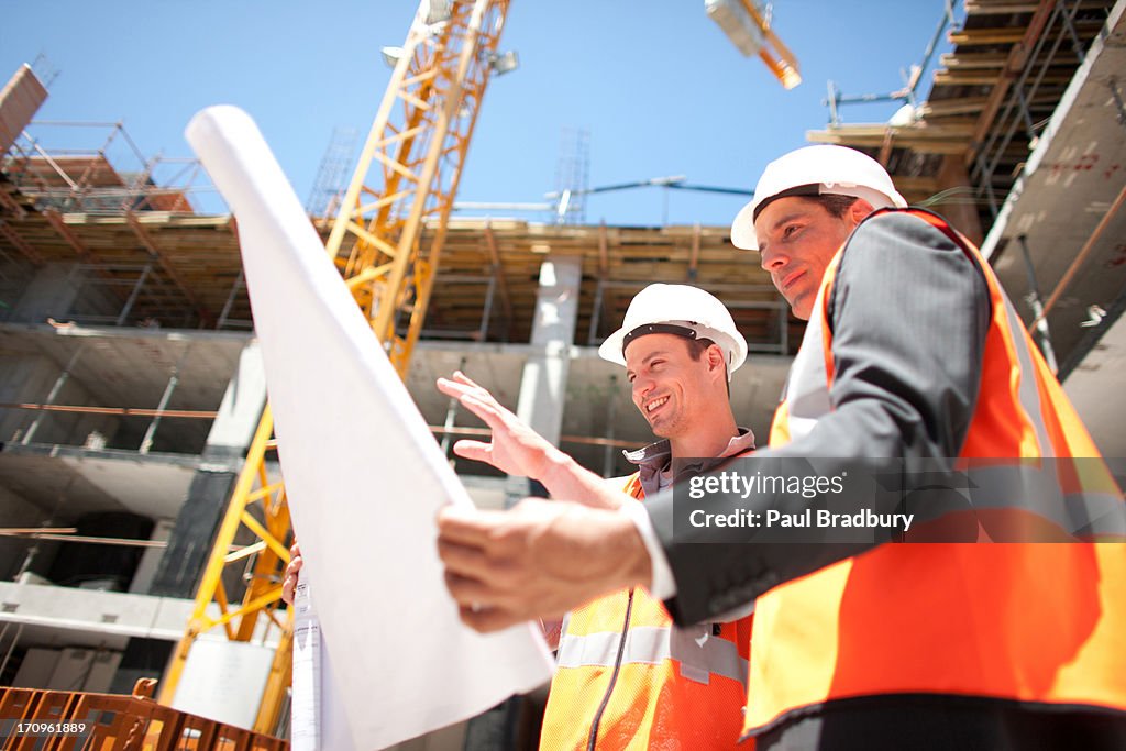 Construction workers looking at blueprints on construction site