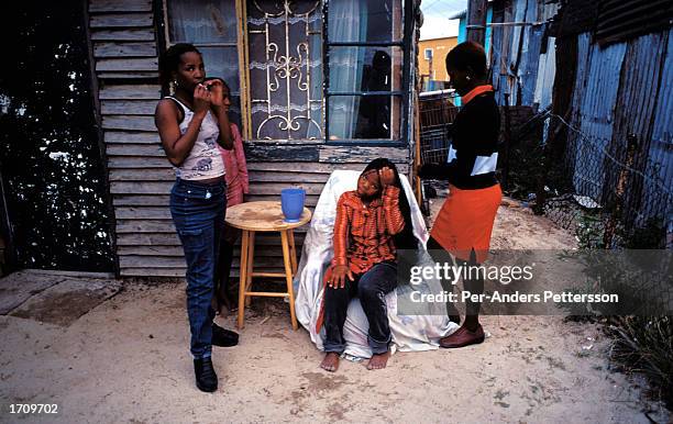 Young women work on each others hair outside their home June 27, 2001 in Site B Khayelitsha, a township about 35 kilometers outside Cape Town, South...