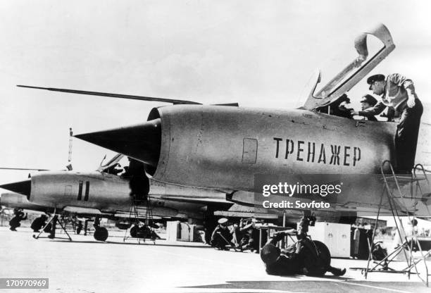 A north vietnamese student pilot in a non-flying mig-21 fighter jet trainer, with him is his soviet flight instructor, lettering on fusilage:...