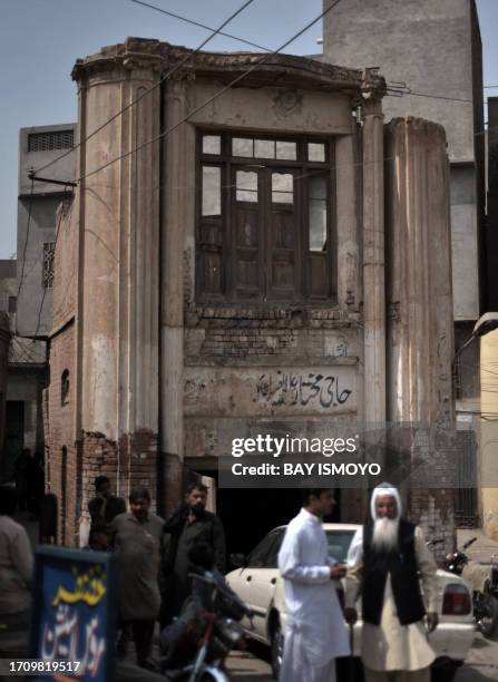 Pedestrians are seen on a street next to a dilapidated building in the old town section of Multan on March 17, 2012. Multan, one of the oldest cities...