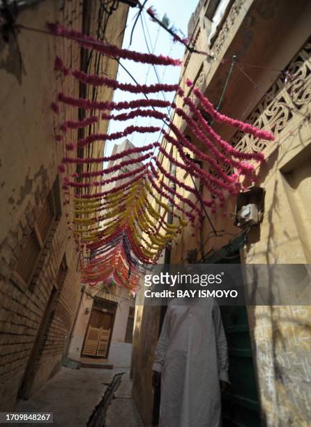 Resident stands underneath decorations hung in a narrow alleyway in the old town section of Multan on March 17, 2012. Multan, one of the oldest...
