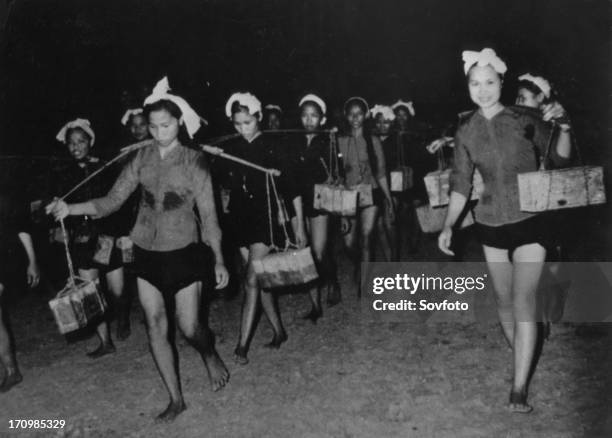Women's unit carrying supplies to the south vietnam people's liberation army forces along the ho chi minh trail at night, vietnam war, 1968.
