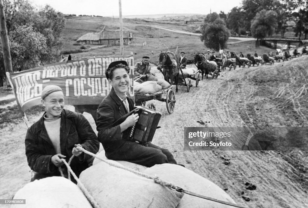 Harvest time on a collective farm in the ussr, august 1947, workers of the vakhitov collective farm taking grain to an elevator in the tatar autonomous soviet socialist republic, the banner reads 'bread from the first harvest goes to the state'.