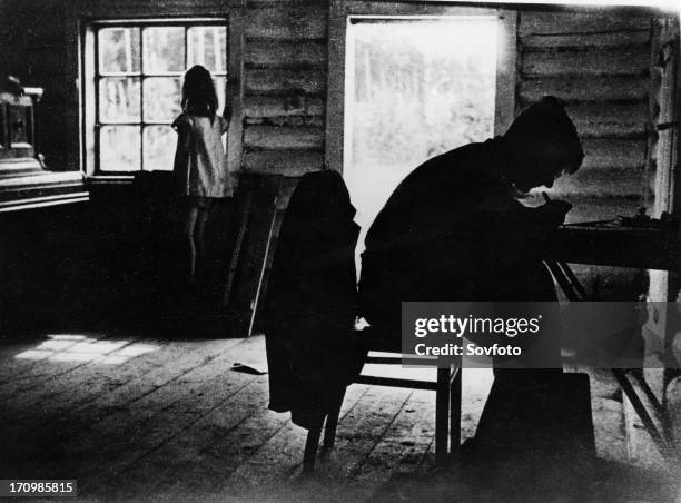 Soviet composer dmitri shostakovich working in his little 'chicken coop' studio, of which he is very fond, as his daughter gazes out of the window,...