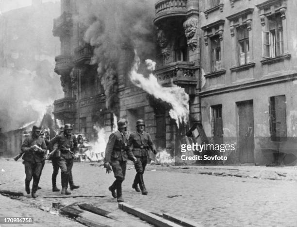 German soldiers walking by fires set in the warsaw ghetto, which was burned to the ground after the uprising, world war ll, poland, 1944.