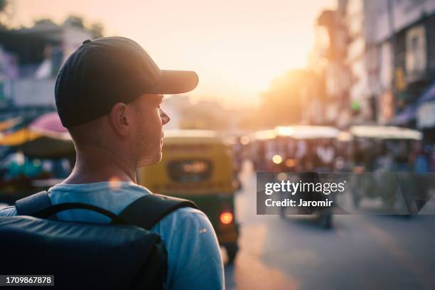 tourist walking down busy street with rickshaws - new delhi street stock pictures, royalty-free photos & images