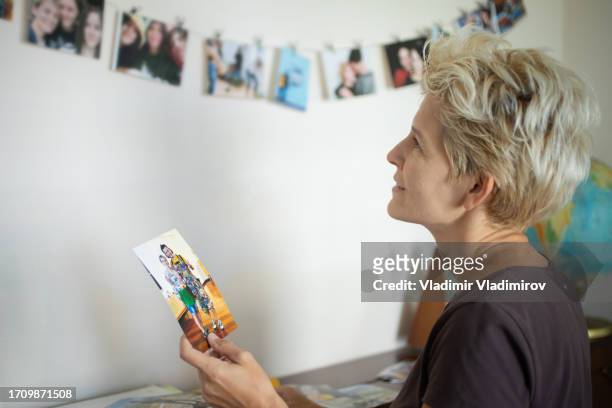 a woman is decorating pictures of her family on the wall - smiley face stock pictures, royalty-free photos & images