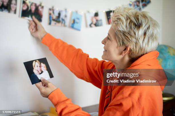 a woman is decorating pictures of her family on the wall - smiley face stock pictures, royalty-free photos & images