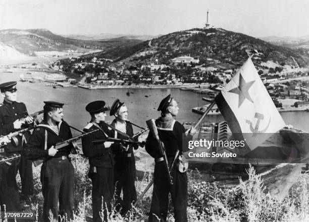 Operation august storm , a landing party of sailors of the soviet pacific fleet hoisting a flag over port arthur bay, manchuria, september 1945.