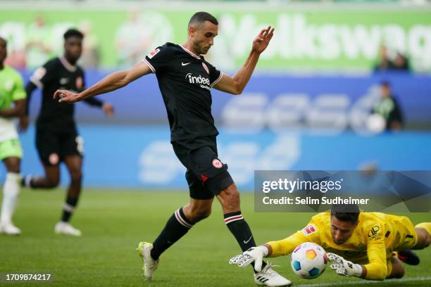 Koen Casteels of VfL Wolfsburg dives at the feet of Ellyes Skhiri of Eintracht Frankfurt during the Bundesliga match between VfL Wolfsburg and...