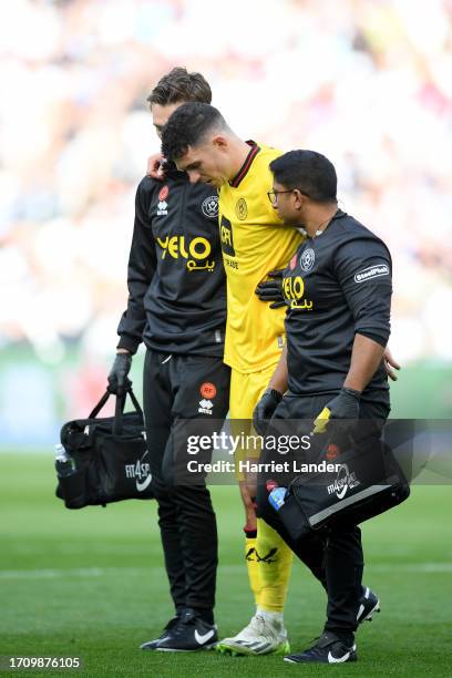 John Egan of Sheffield United leaves the field after receiving medical treatment to an injury during the Premier League match between West Ham United...