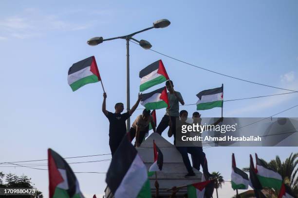 Palestinians raise national flags and banners during a demonstration on the 23rd anniversary of the Al-Aqsa Mosque Intifada and the conditions they...