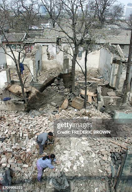 Workers collect bricks from amid the rubble of a destroyed neighborhood, 28 March 2002 in Beijing. While old neighborhoods are fast disappearing to...