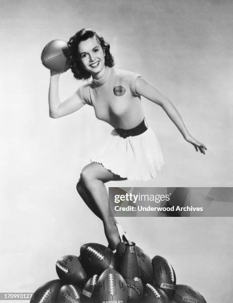 Actress Debbie Reynolds gets ready to throw a pass to kick off the football season, Hollywood, California, 1953.