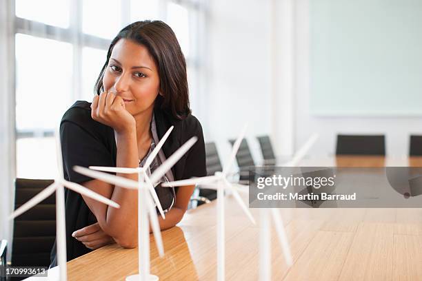 businesswoman sitting in conference room with model turbines - small wind turbine stockfoto's en -beelden