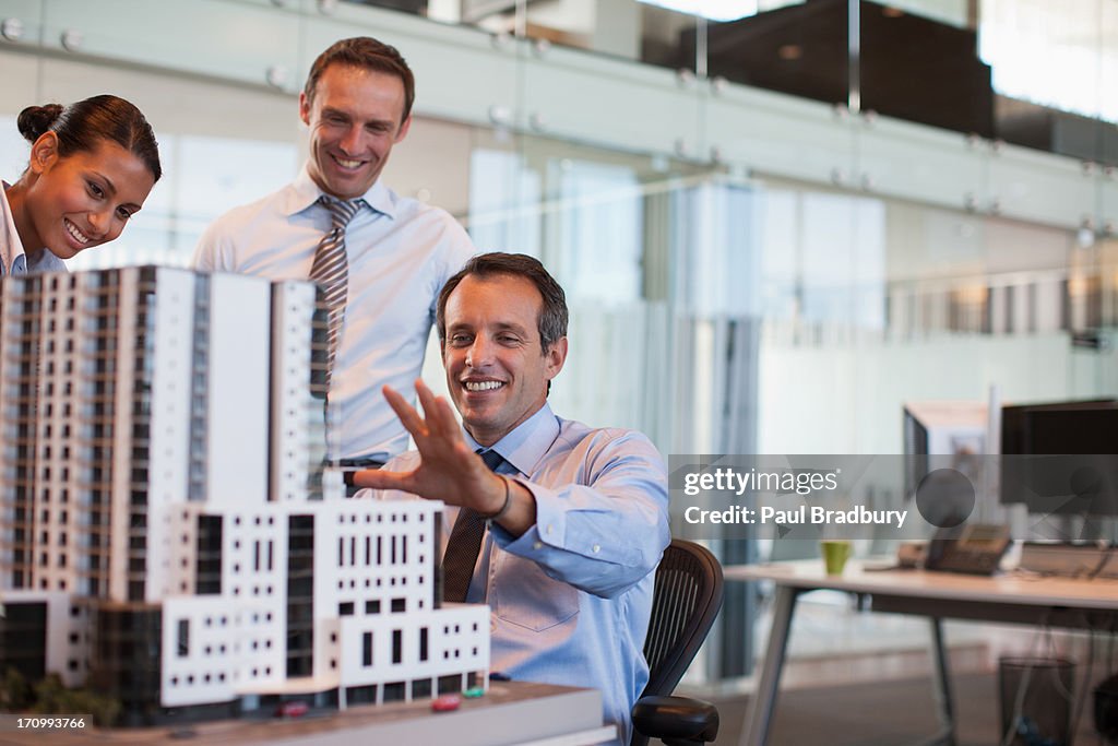 Business people looking at model building in office