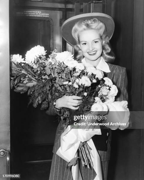 Betty Grable is presented with flowers as she arrives at Grand Central Station in New York City, New York, New York, 1942.
