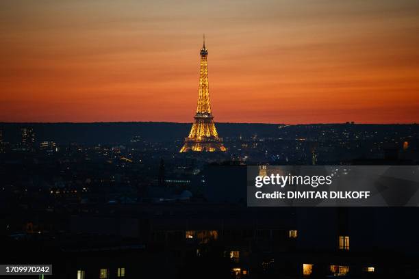 Photograph shows the Eiffel Tower being illuminated at sunset in Paris on October 6, 2023.