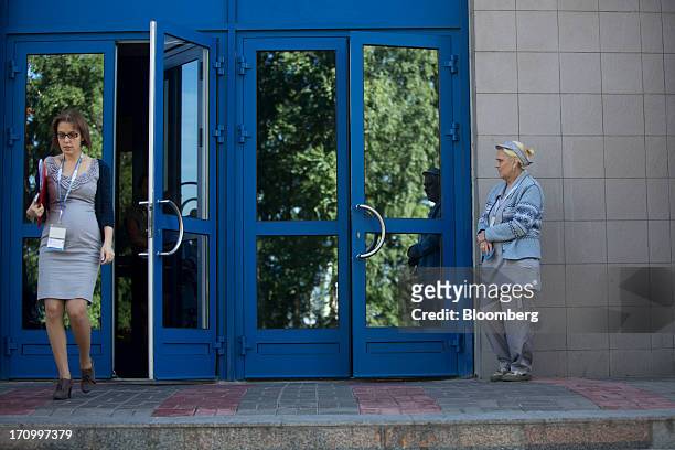 Cleaner, right, waits to clean windows as delegates pass through a doorway at the Lenexpo center on the opening day of the St. Petersburg...