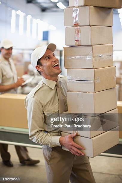 worker carrying stack of boxes in shipping area - carrying box stock pictures, royalty-free photos & images