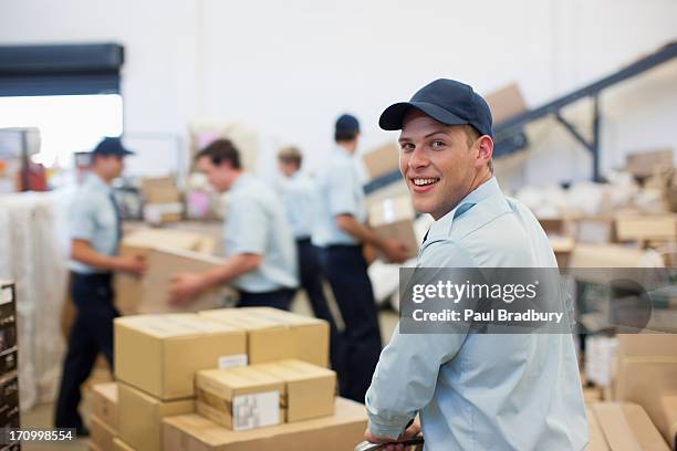 trabajador moviendo cajas en mano carrito en el área de envíos - gorra de béisbol fotografías e imágenes de stock