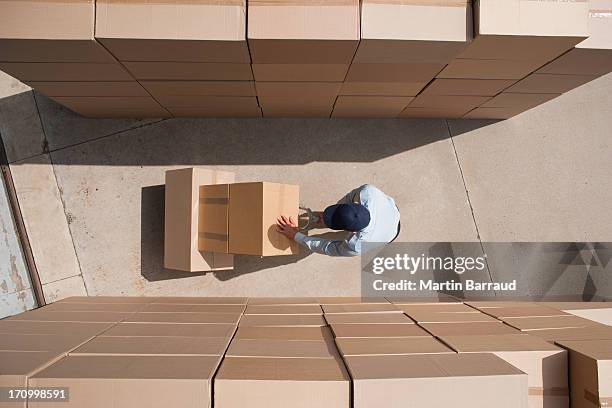 worker standing with boxes and hand truck - postbode stockfoto's en -beelden