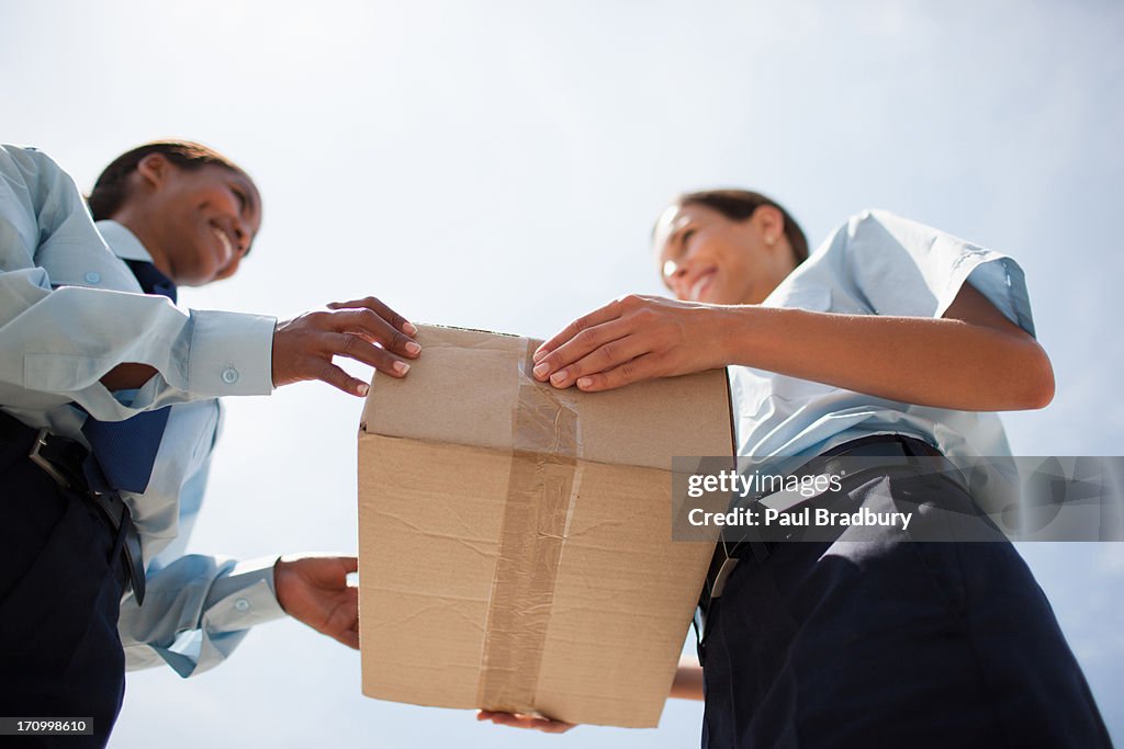 Supervisor handing box to worker
