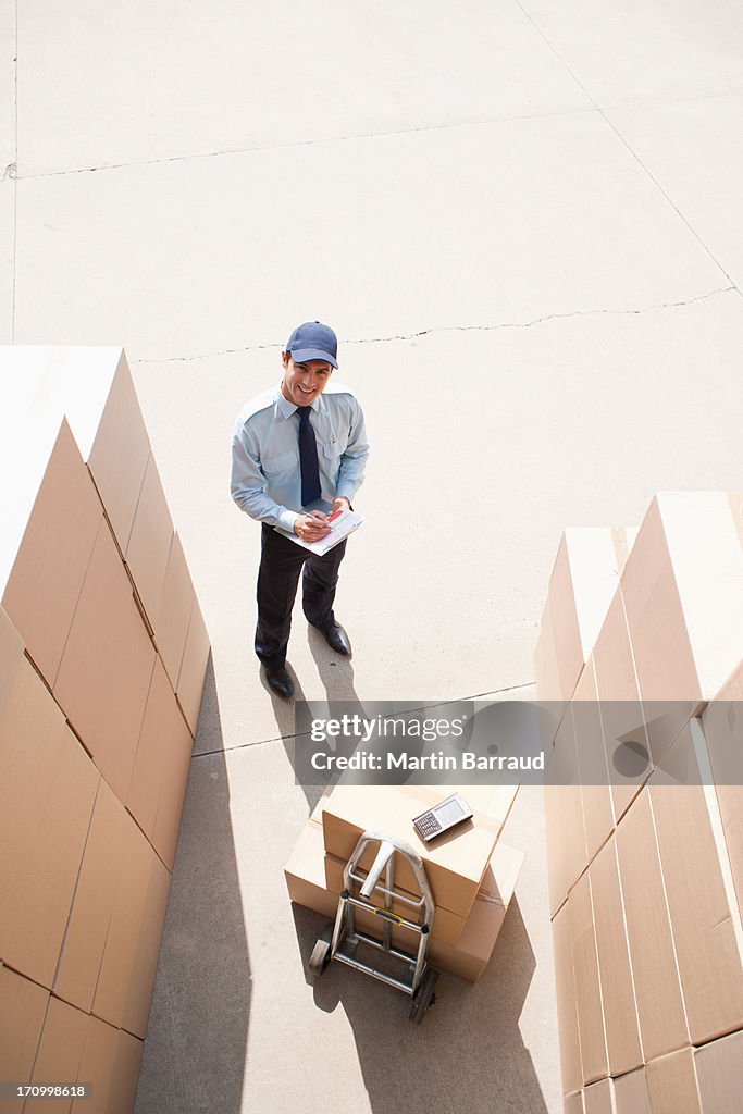 Worker standing with boxes and hand truck