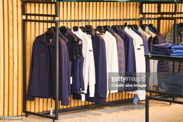 pile of clothes hanging from hooks in a public warehouse or store with no people, side view - clothing store stock pictures, royalty-free photos & images