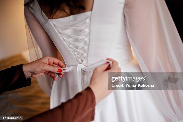 bridesmaid buttoning up bride's wedding dress - backless dress stock pictures, royalty-free photos & images