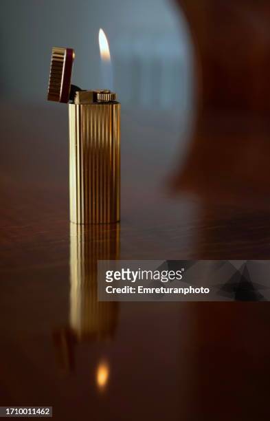 close up of a gold lighter on wooden table. - premium lighter stock pictures, royalty-free photos & images